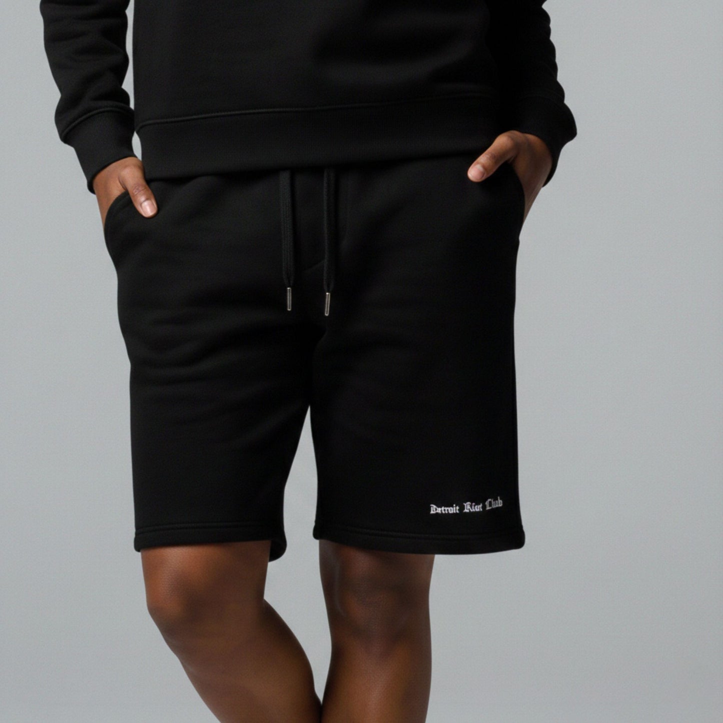 "Female model wearing the Detroit Riot Club 8.5oz Archival Jogger Shorts in Void Black. Showcases the unisex oversized fit and premium heavyweight drape."