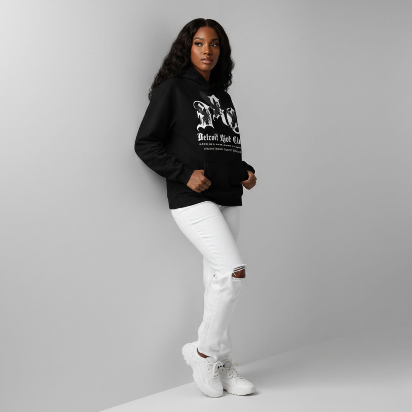 "Female model highlighting the relaxed, unisex oversized fit of the Legacy Crest Hoodie. 100% cotton face hardware designed for comfort and daily Motor City resilience."