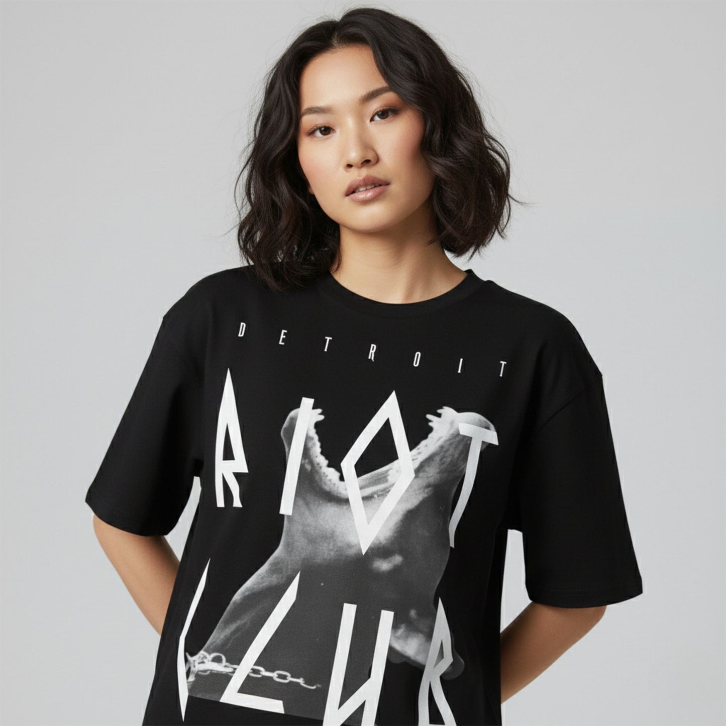 Person wearing a black t-shirt with graphic design and text on a plain background