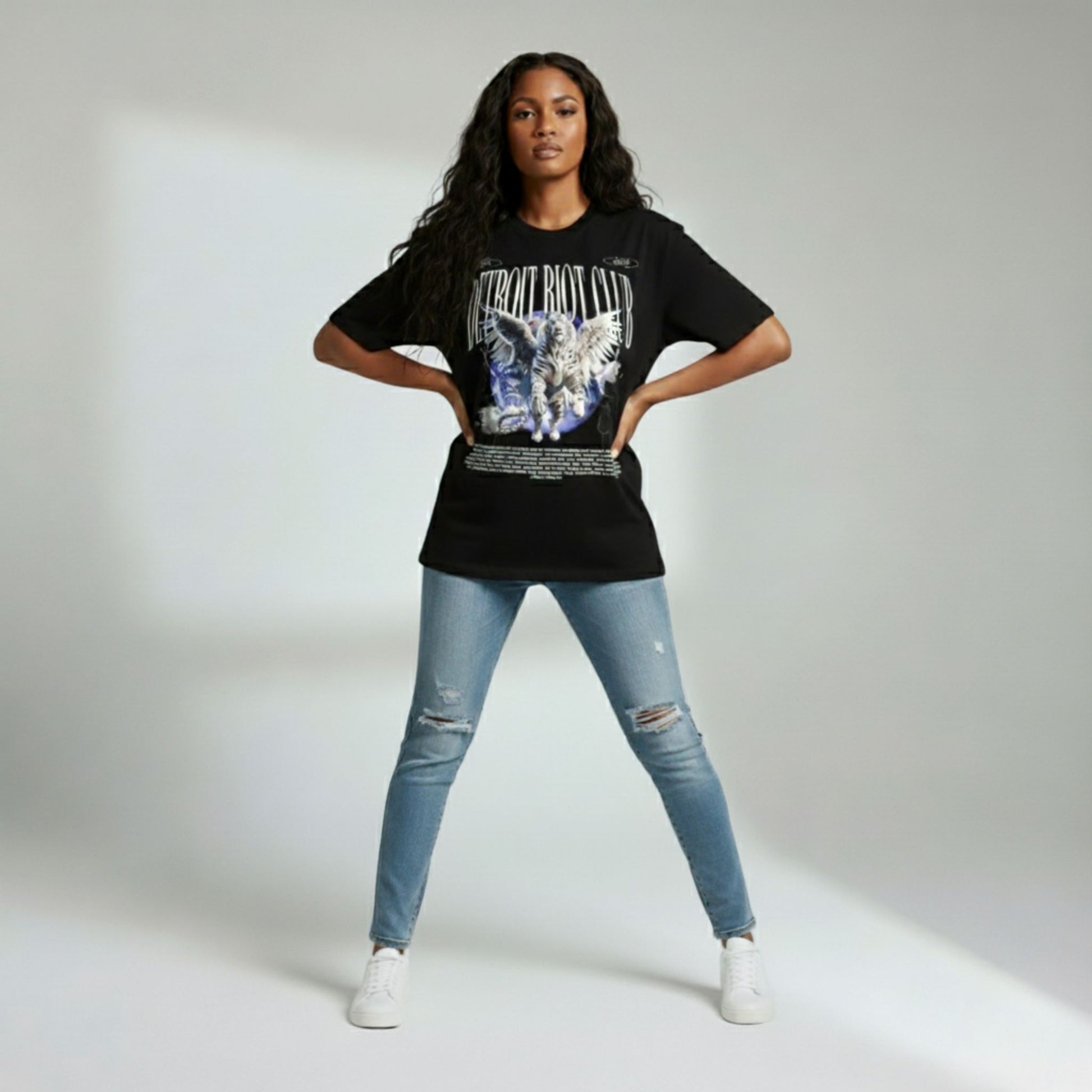 Person wearing a black t-shirt with a graphic design and blue jeans on a plain background