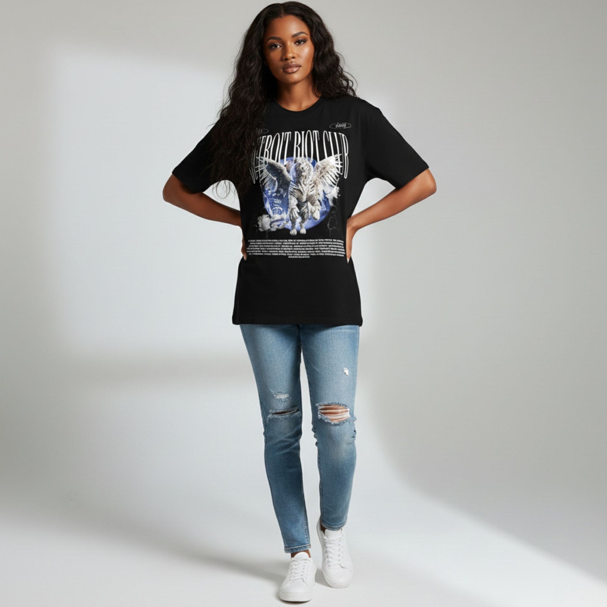 Person wearing a black t-shirt with graphic design and blue jeans on a white background